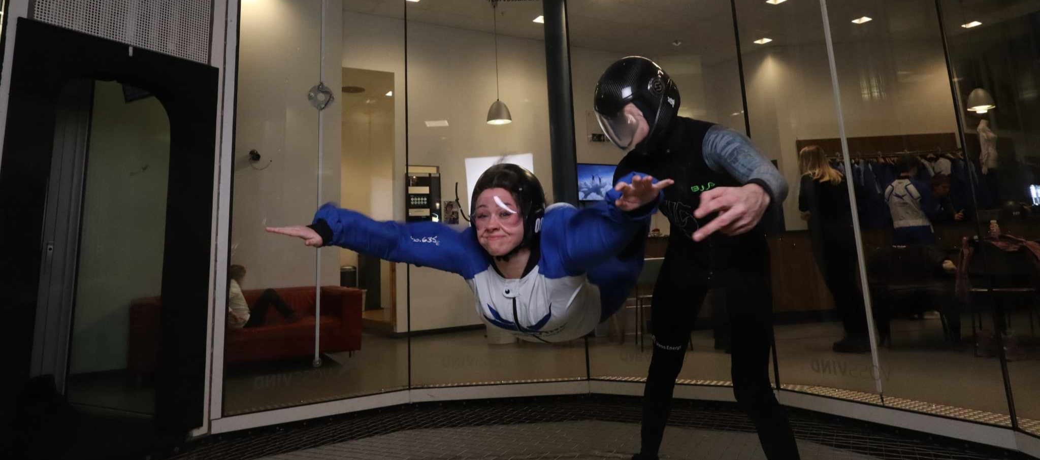 A picture of a young woman flying in a inside windtunnel.