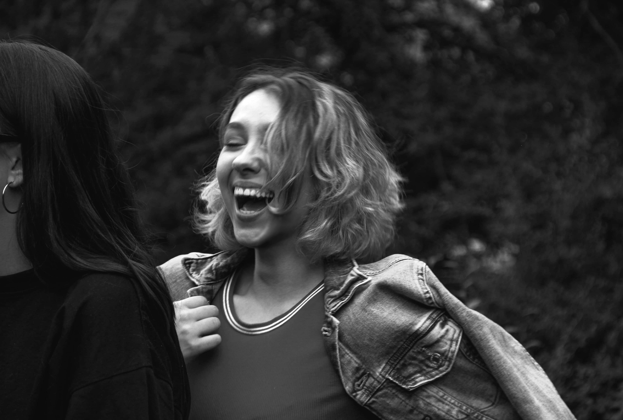 A picture of a young woman smiling with open more with a black and white filter.